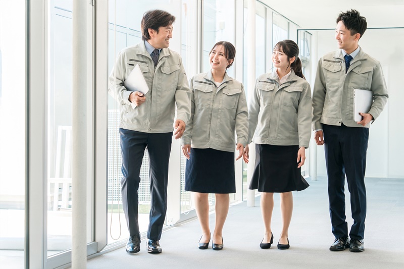 作業着を着た従業員同士が楽しそうに談笑しながら歩いている